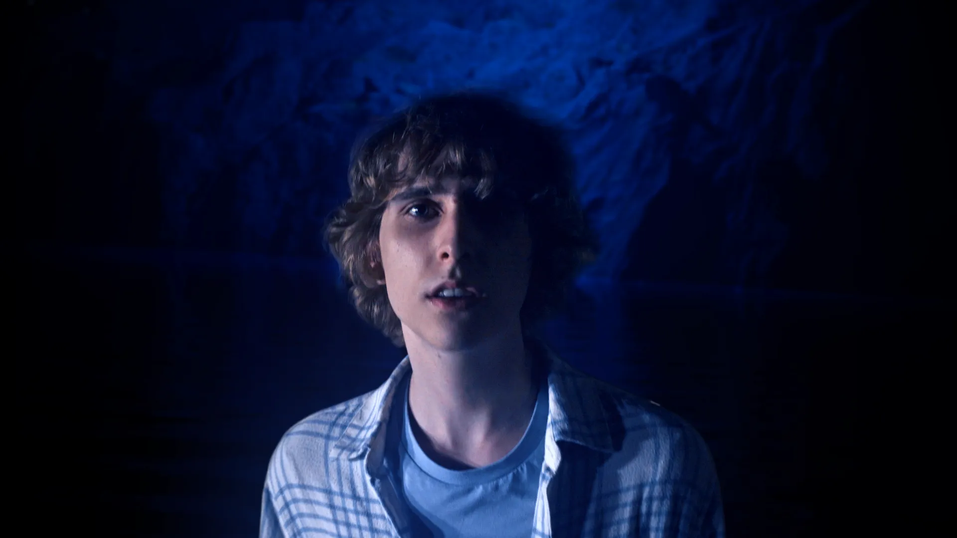 A picture of Misha standing in a blue watery cave.